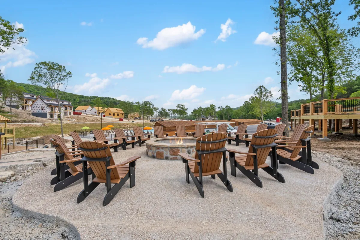 A cozy fire pit surrounded by Adirondack chairs set amidst natural surroundings. The scene suggests guests gathered around, sharing stories and relaxing in the tranquil outdoors.