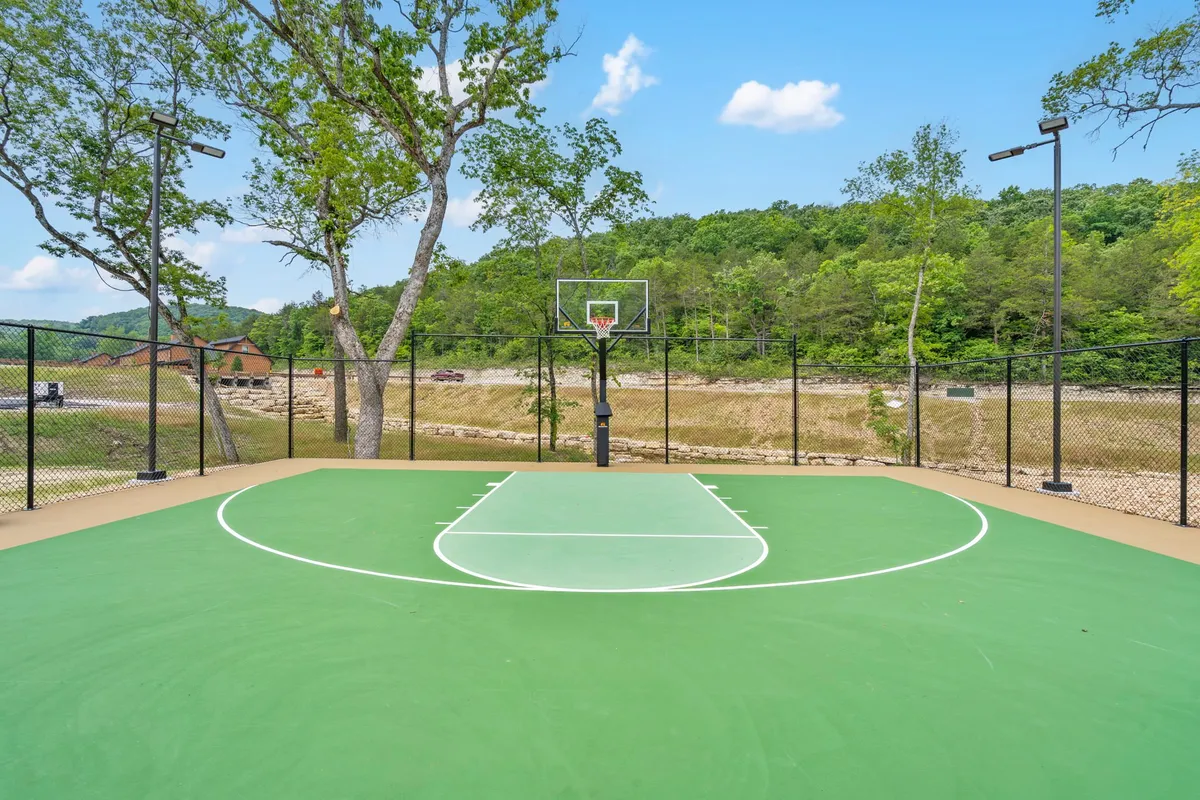 A vibrant exterior shot of a basketball court framed by trees and mountain views. Friends or families can gather here for energetic games, socializing, and creating new traditions together.